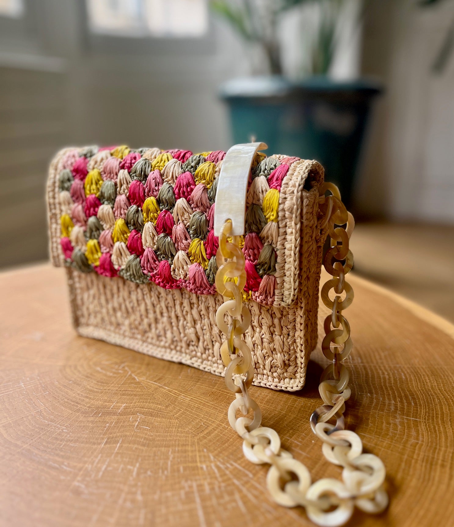 Sac artisanal en raphia naturel orné d'une chaîne en corne, design chic et naturel, idéal pour compléter vos tenues.