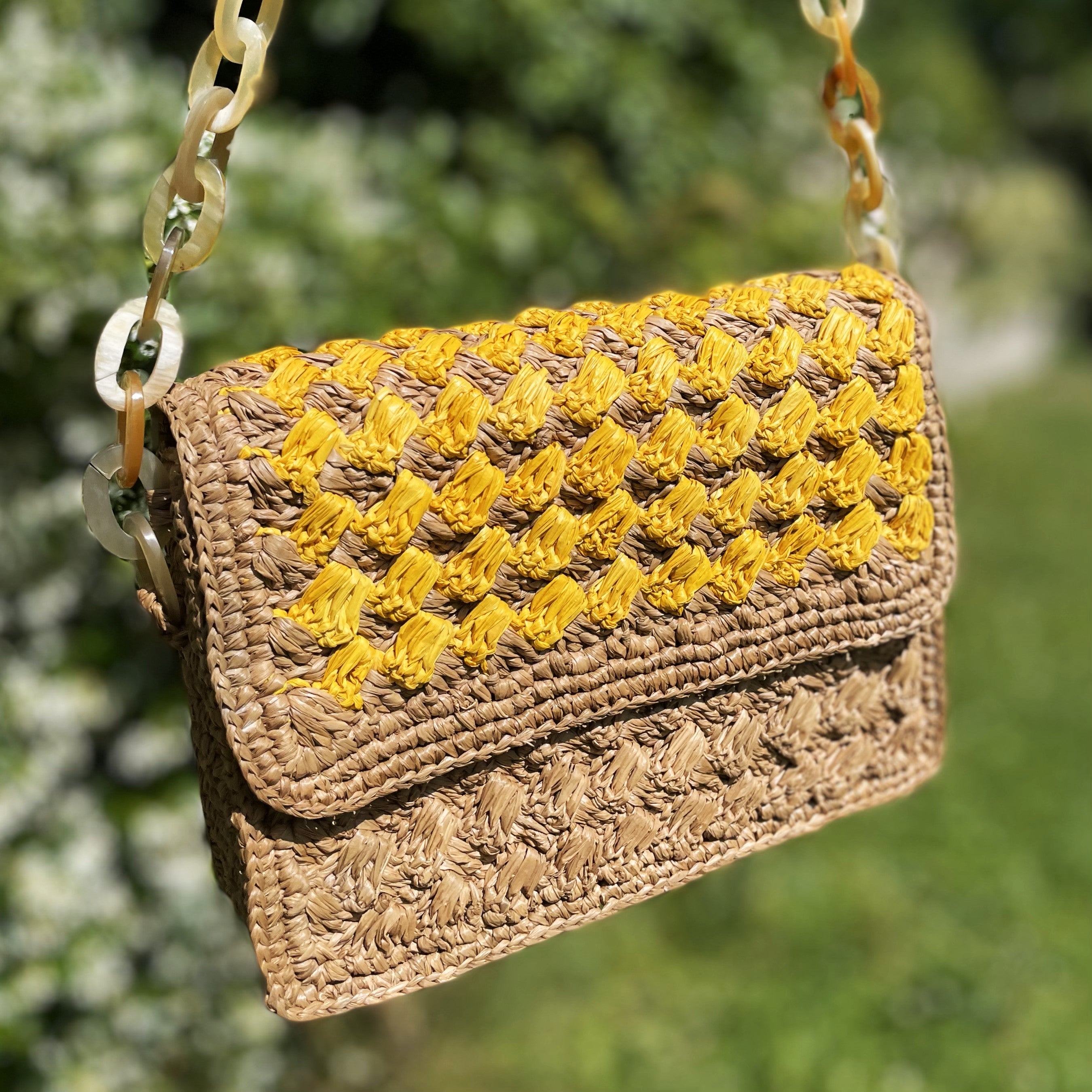 Sac artisanal en raphia avec détails en corne, teinte jaune, parfait pour une allure sophistiquée et estivale.