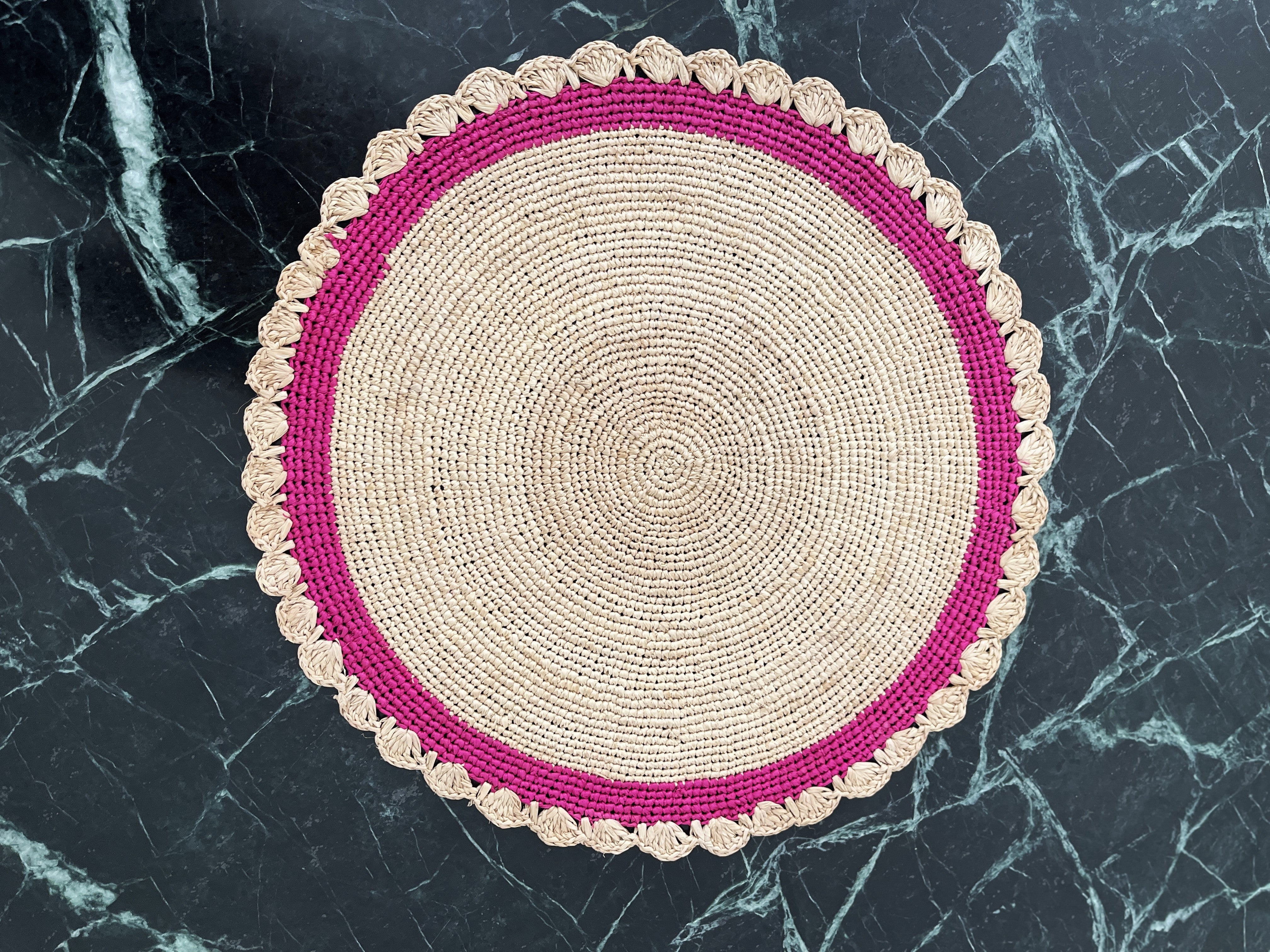 Ensemble artisanal de sets de table ronds en raphia naturel bordure rose, apportant charme et originalité à votre intérieur.