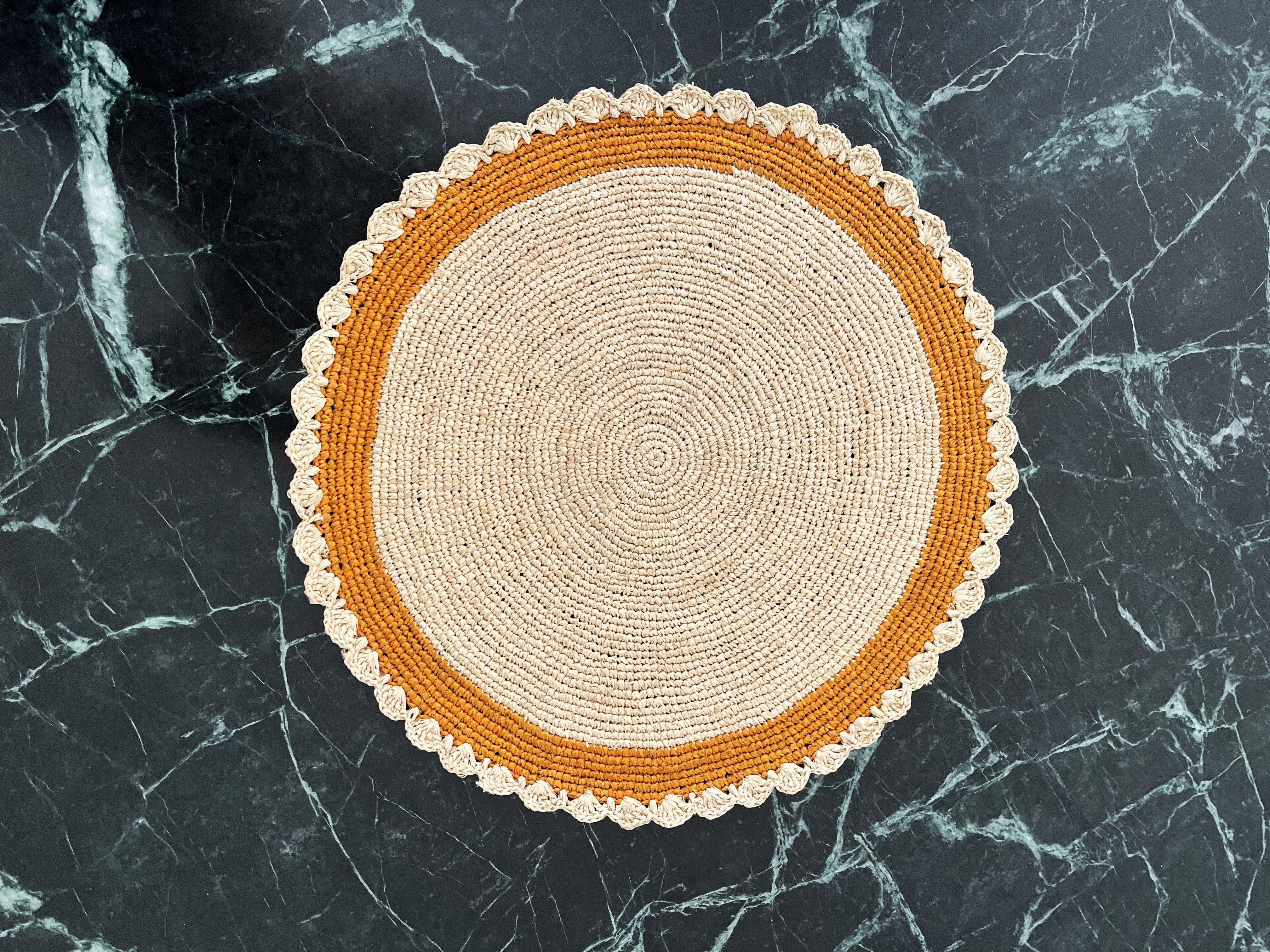 Set rond en raphia naturel avec bordure jaune, artisanal et unique, parfait pour des repas colorés et chaleureux.