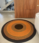 Tapis rond unique en raphia, tons orange, brun et noir, fait main à Madagascar, diamètre 200 cm, parfait pour un style authentique.