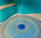 Tapis rond en raphia aux nuances jaune, bleu, turquoise et vert émeraude, fait main à Madagascar, diamètre 200 cm.