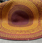 Tapis rond en raphia fait main à Madagascar, aux nuances sophistiquées de jaune, brun et prune, diamètre 230 cm.