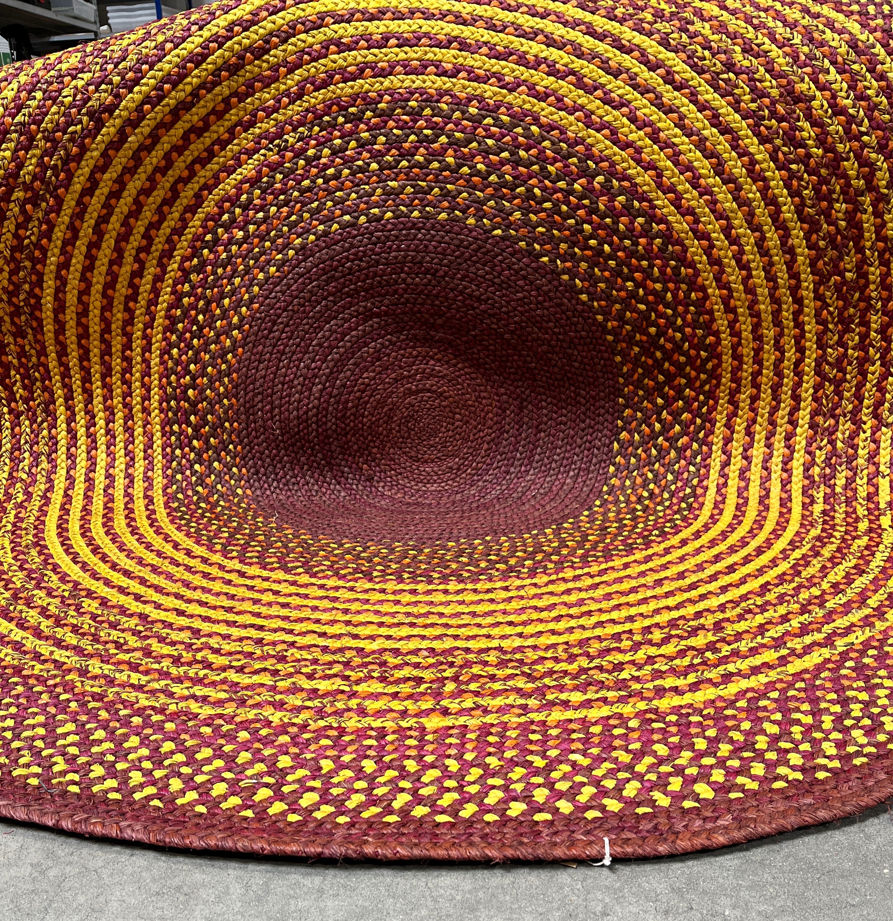Tapis rond en raphia fait main à Madagascar, aux nuances sophistiquées de jaune, brun et prune, diamètre 230 cm.