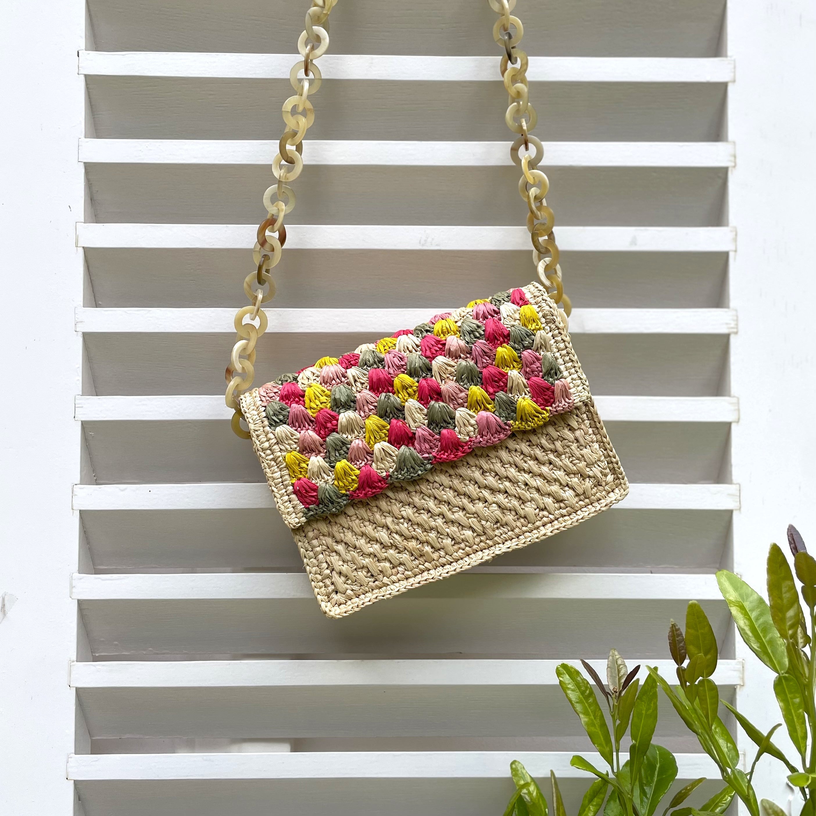 Sac à main en raphia naturel avec chaîne en corne, fait main, alliant simplicité et élégance pour un style intemporel.