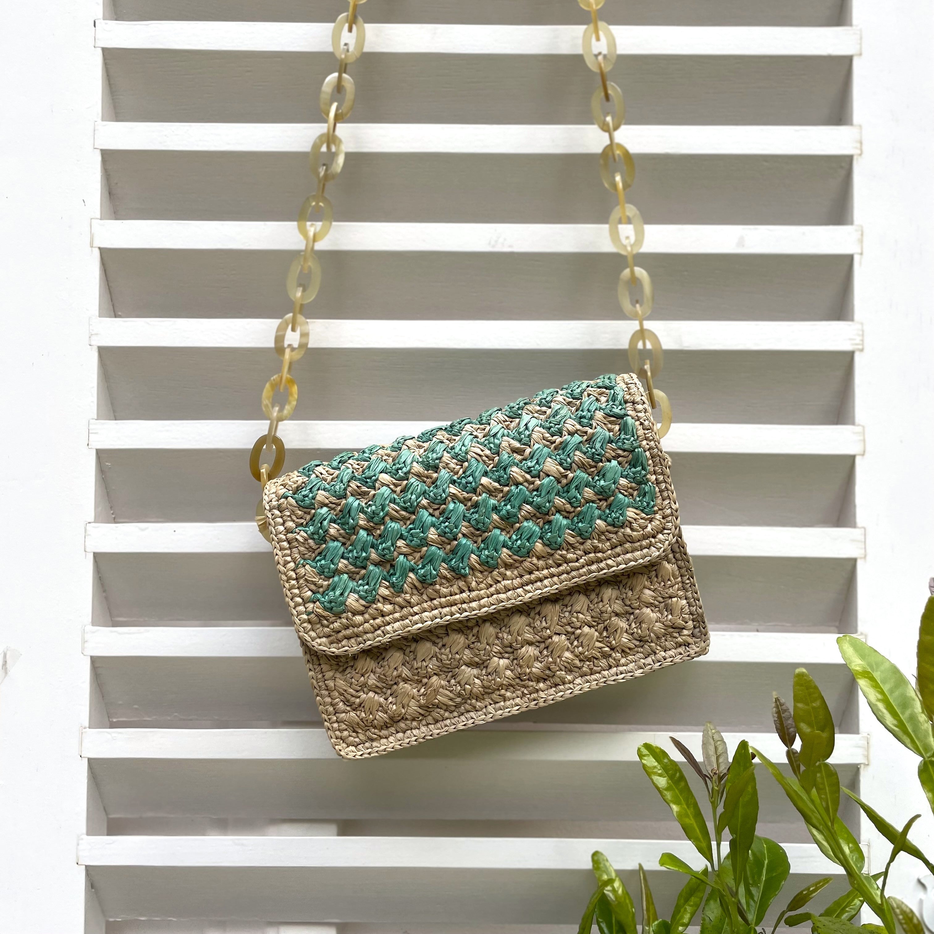 Sac à main artisanal en raphia turquoise, avec finitions en corne, idéal pour un look authentique et coloré.