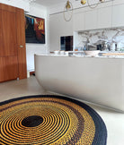 Tapis artisanal en raphia, combinaison de noir, jaune et terracotta, rond, 200 cm, parfait pour un intérieur chaleureux.