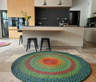 Tapis rond en raphia avec motifs verts, bleus, turquoise, orange et rouge, diamètre 180 cm.